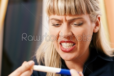 woman doing pregnancy test being unhappy