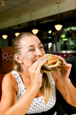 Woman in a restaurant eating hamburger