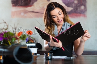 Woman in restaurant choosing food in menu
