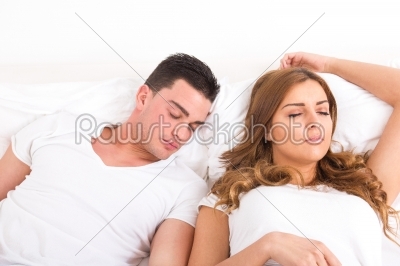 Young beautiful couple sleeping together in bed