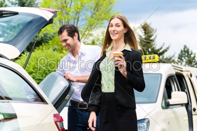Young businesswoman in front of taxi