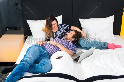 Young couple in Hotel in bed with wifi and computer