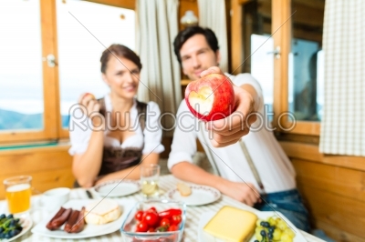 Young couple in mountain chalet eating