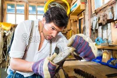 Young man sharpening tools in mountains hut