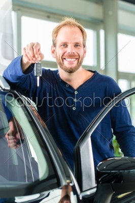 Young man with auto in car dealership