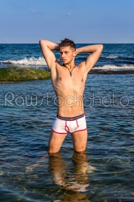 Young sexy man standing in sea water