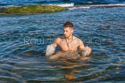 Young sexy man standing in sea water