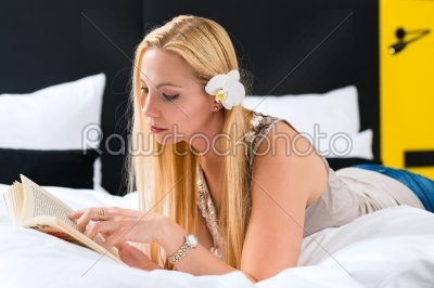 Young woman in Hotel reading book in bed