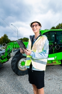 architect in front of excavator using pad or tablet