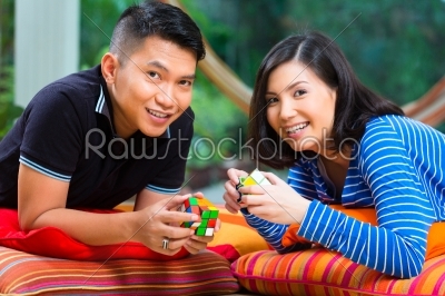 Asian couple at home playing with magic cube