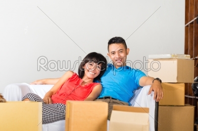 Asian couple having break while moving in