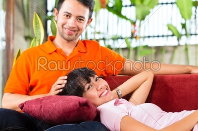 Asian couple in spacious home on sofa