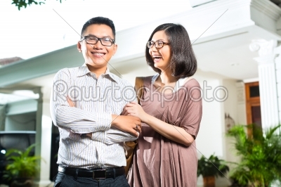 Asian homeowner couple in front of home