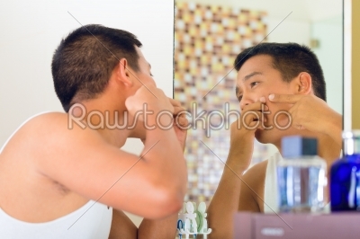 Asian man discovering a pimple in face