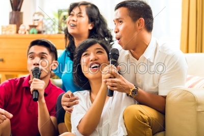 Asian people singing at karaoke party and having fun