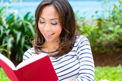 Asian woman at home in garden reading book