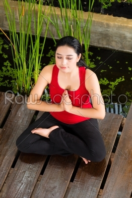 Asian woman doing yoga in tropical setting