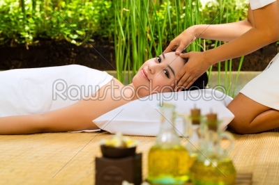 Asian woman having a massage in tropical setting