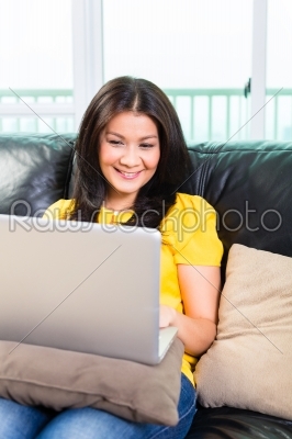 Asian woman using laptop on couch