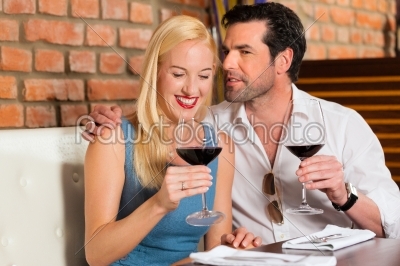 Attractive couple drinking red wine in restaurant or bar