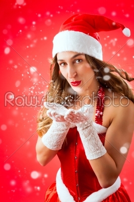 Attractive woman as Santa Claus blowing snow