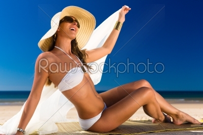 Attractive woman in a bikini smiles at the sun at the beach
