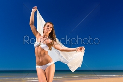 Attractive woman stands in the sun on beach
