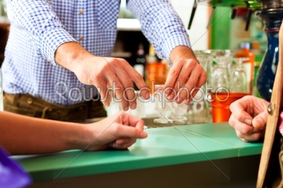 Barkeeper pouring hard liquor in glasses
