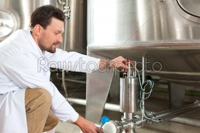Beer brewer in his brewery at food tank