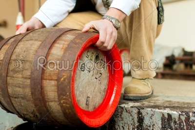 Brewer with beer barrel in brewery