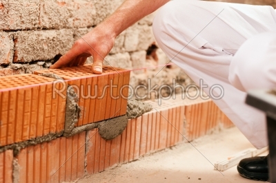 bricklayer making wall with brick and grout