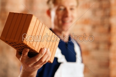 bricklayer with brick on construction site