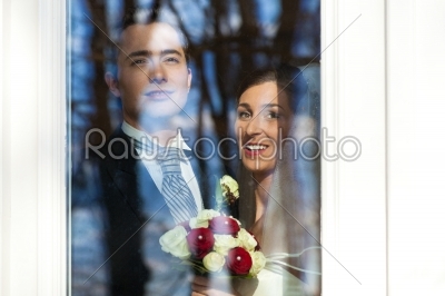 Bridal couple standing at the window at their wedding