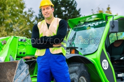 Builder in front of  construction machinery