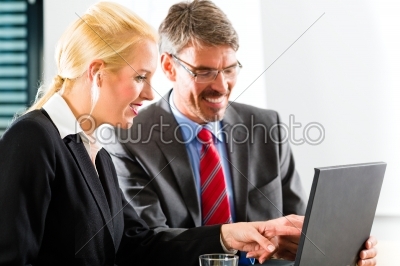 Businesspeople looking at laptop in consultation