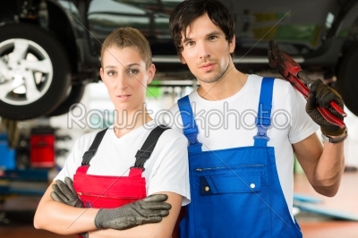 Car mechanics male and female in front of auto