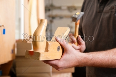 Carpenter with wood planer and hammer