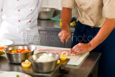 Chefs preparing fish in restaurant or hotel kitchen
