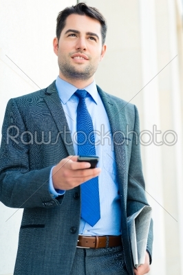 Confident businessman outdoor using phone