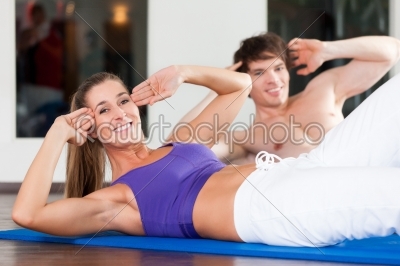 Couple doing sit ups in gym