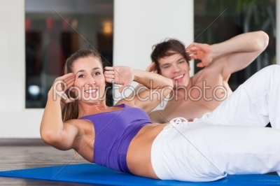 Couple doing sit ups in gym
