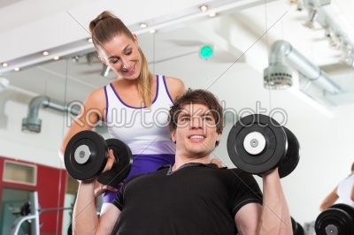 Couple exercising in gym with weights
