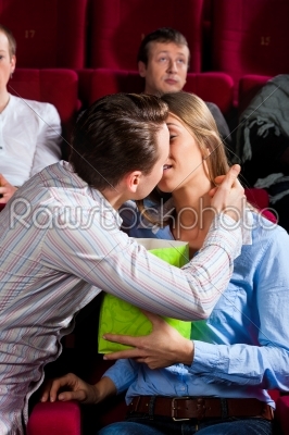 Couple in cinema with popcorn kissing