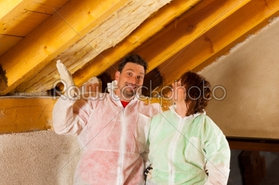 Couple installing thermal insulation to roof