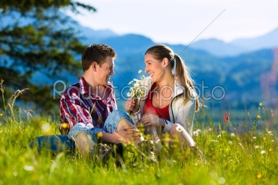 Couple is sitting in the meadow with mountain
