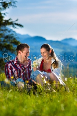 Couple is sitting in the meadow with mountain