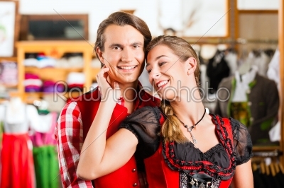 Couple is trying Dirndl or Lederhosen in a shop