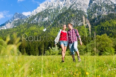 Couple is walking in the meadow with mountain