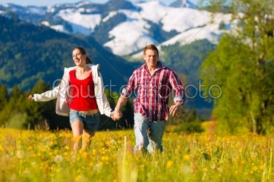 Couple running in the meadow with mountain