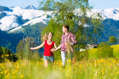 Couple running in the meadow with mountain